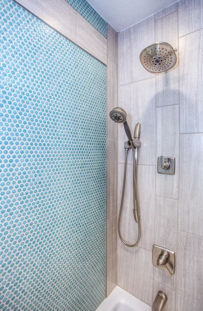 A tall shower with a blue mosaic tile wall